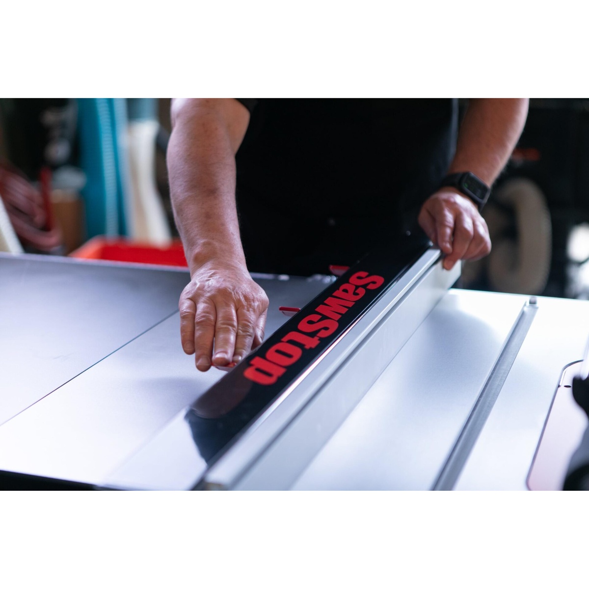 SawStop ATGI-FA Industrial T-Glide Advance Rip Fence being adjusted by hand on a SawStop industrial cabinet saw during table saw setup in a woodworking shop