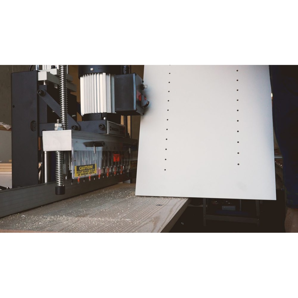 Maksiwa LBP.13 Pneumatic Line Boring Machine drilling evenly spaced holes in a white cabinet panel on a woodworking bench
