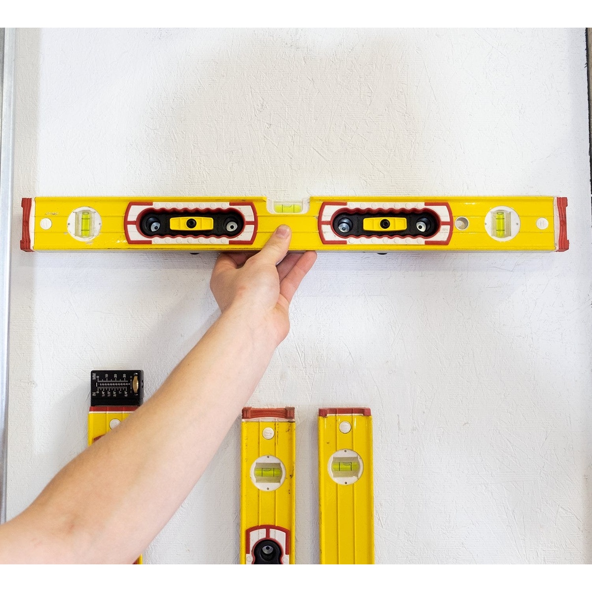 Fastcap Level Rack for Updated Stabila Level Handles holding a long Stabila level horizontally on a shop wall for organized storage