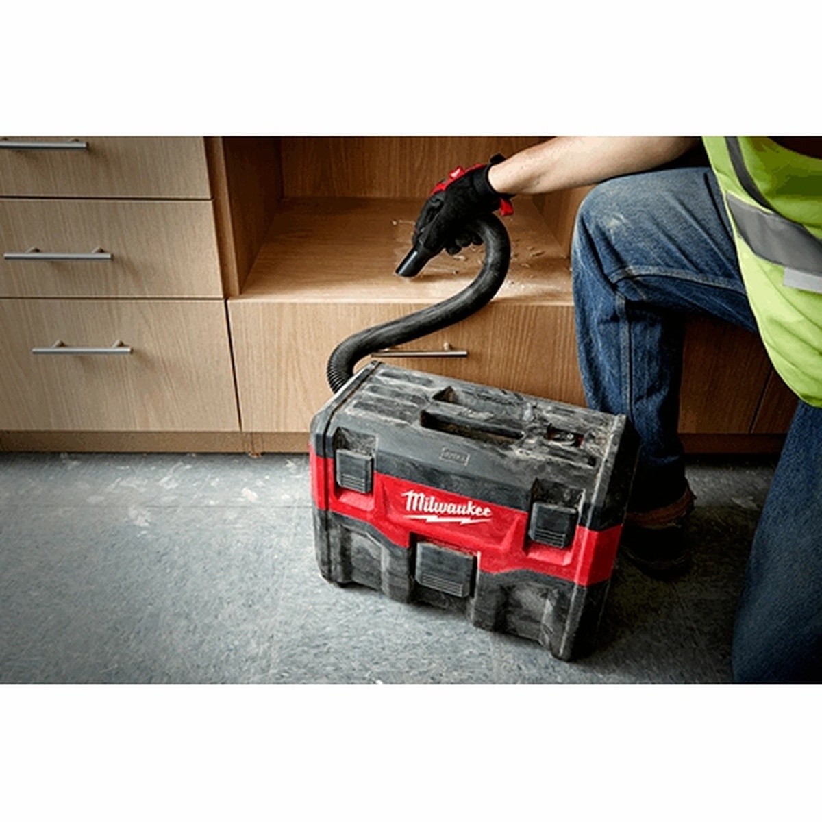 Milwaukee 0880-20 M18 2-Gallon Wet/Dry Vacuum cleaning dust beside cabinets during interior finish work on a jobsite