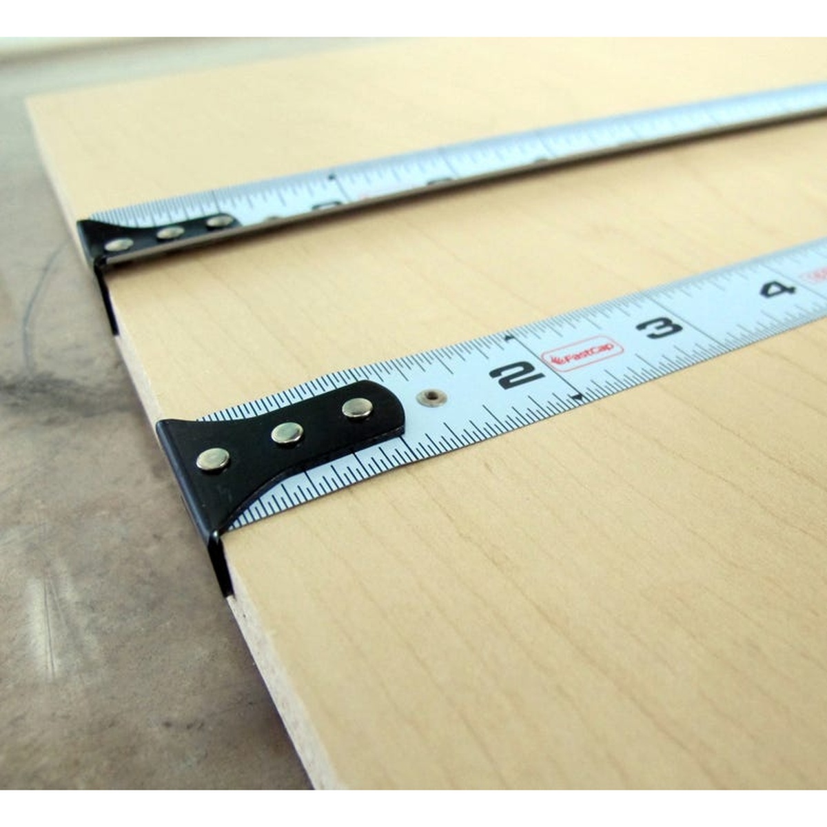 FastCap Lefty/Righty Flatback Tape Measure, Imperial laid across a wood panel for flat layout work on sheet material