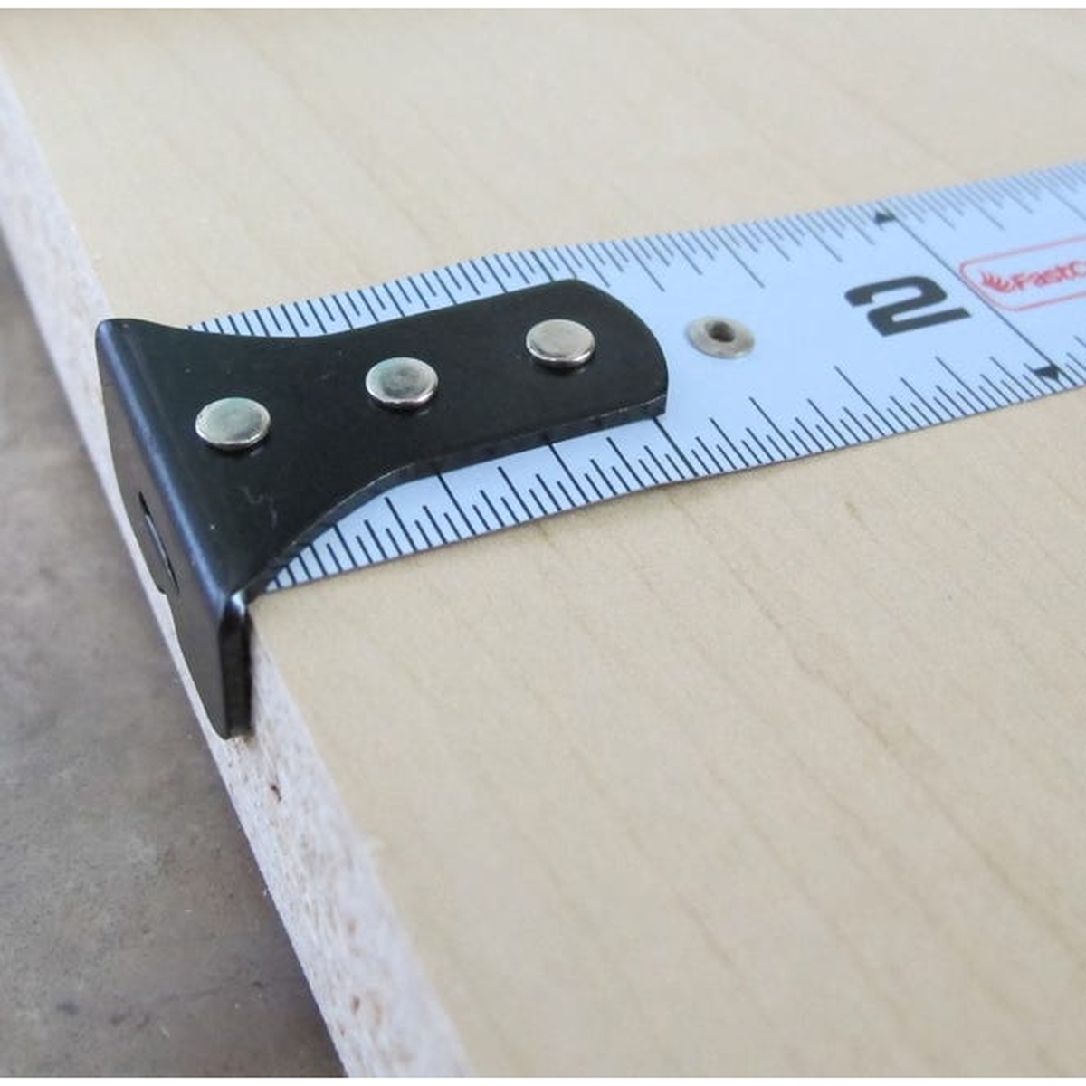 FastCap Lefty/Righty Flatback Tape Measure, Imperial close-up of the hook and blade on a wood panel during layout work