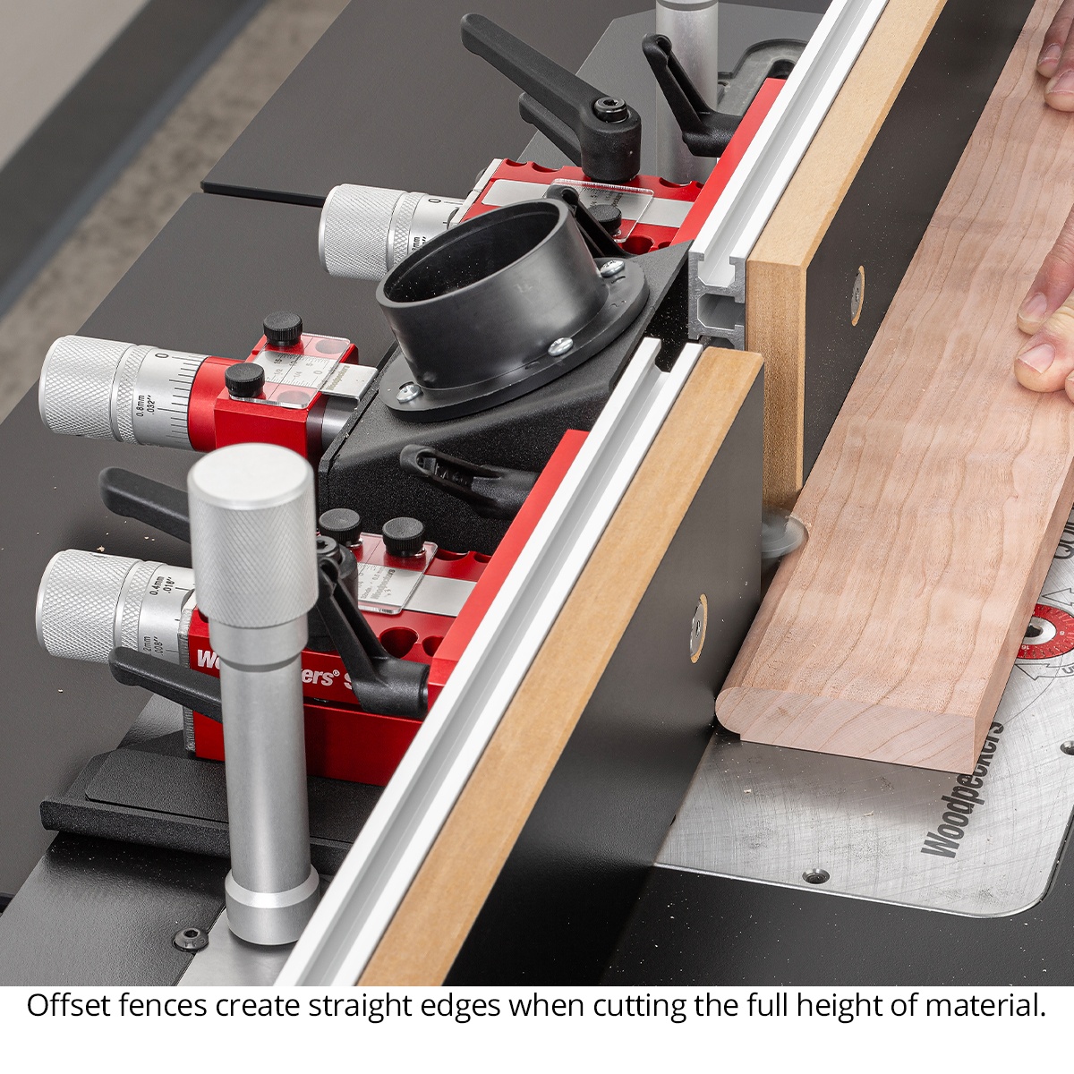 Woodpeckers SF-PRO Universal Router Table Fence guiding a wood board during routing on a router table, showing offset fence setup and dust collection near the cutter