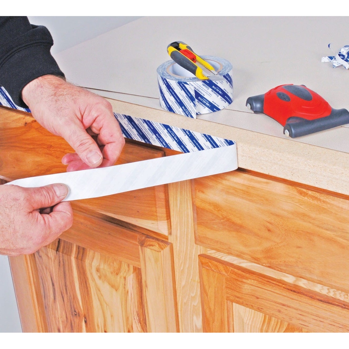 Fastcap SpeedTape 3/4-in. x 50-ft. for Edgebanding with liner peeled back while attaching material to a cabinet edge during installation
