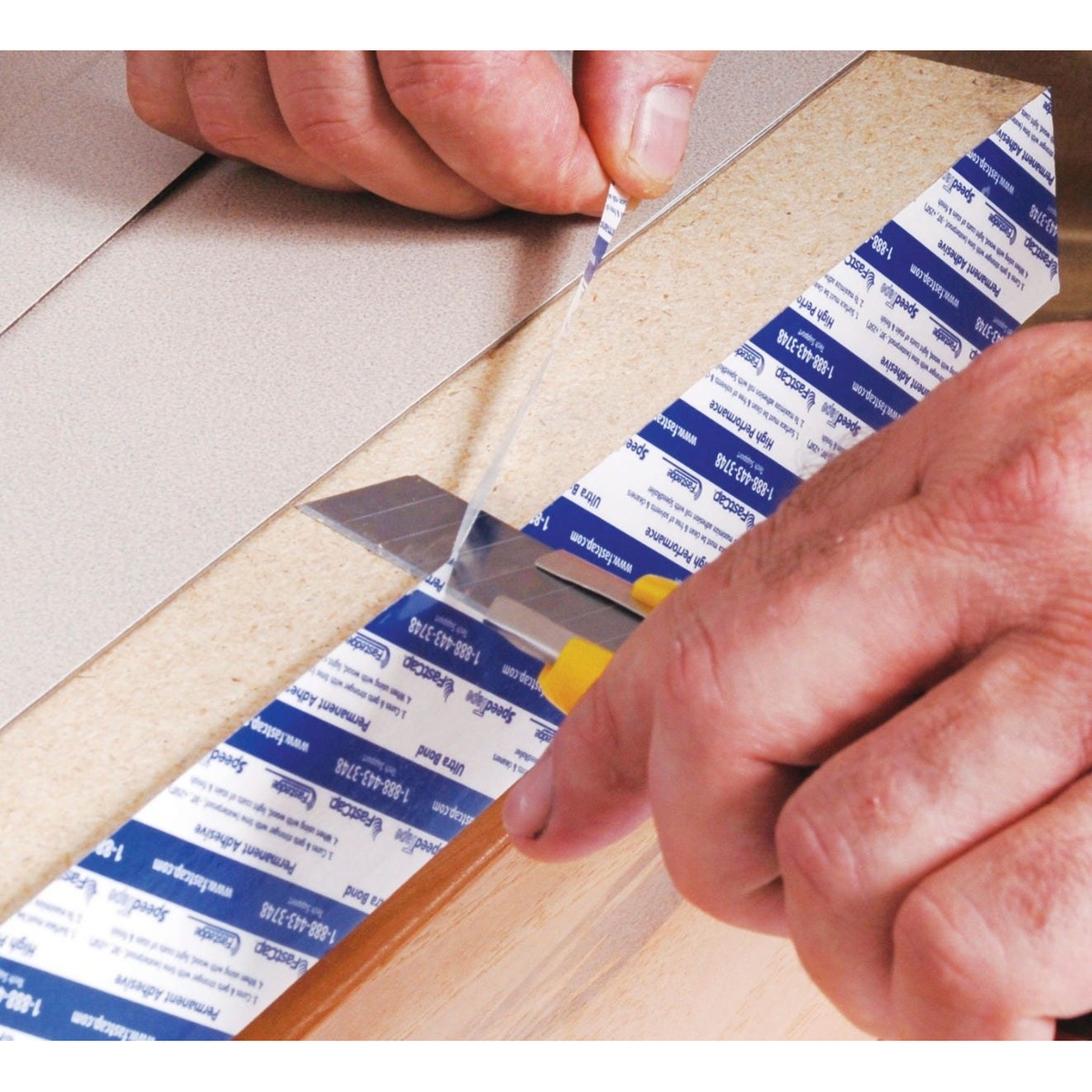 Fastcap SpeedTape 3/4-in. x 50-ft. for Edgebanding being trimmed flush on a cabinet edge with a utility knife in a woodworking shop