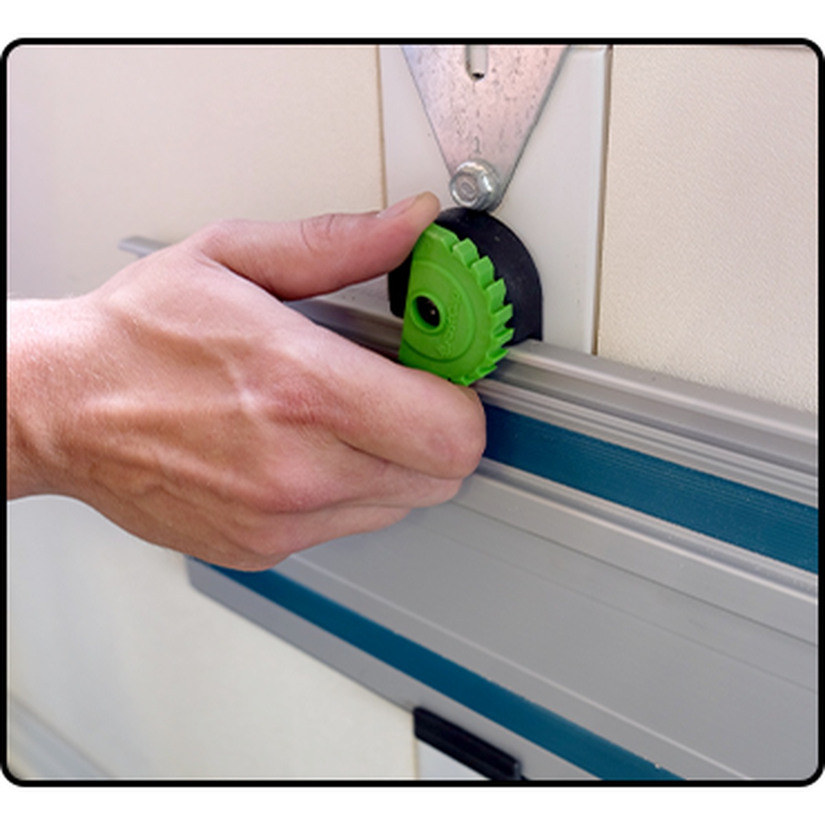 Fastcap Track Rack, 2-Pack holding a track saw guide rail on a wall while a user secures the cam lock in a workshop setting