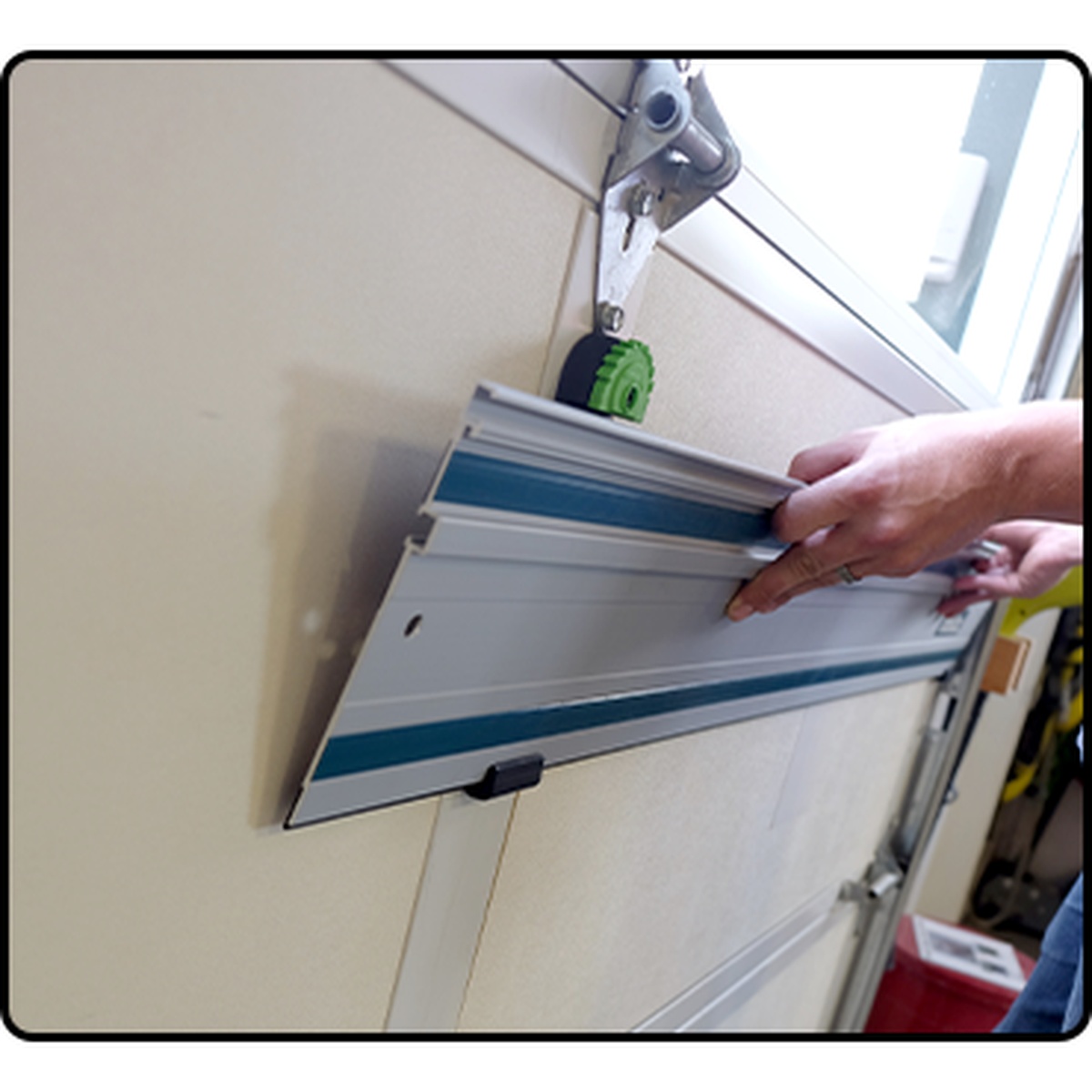 Fastcap Track Rack, 2-Pack mounted on a garage door storing track saw rails horizontally for compact shop organization