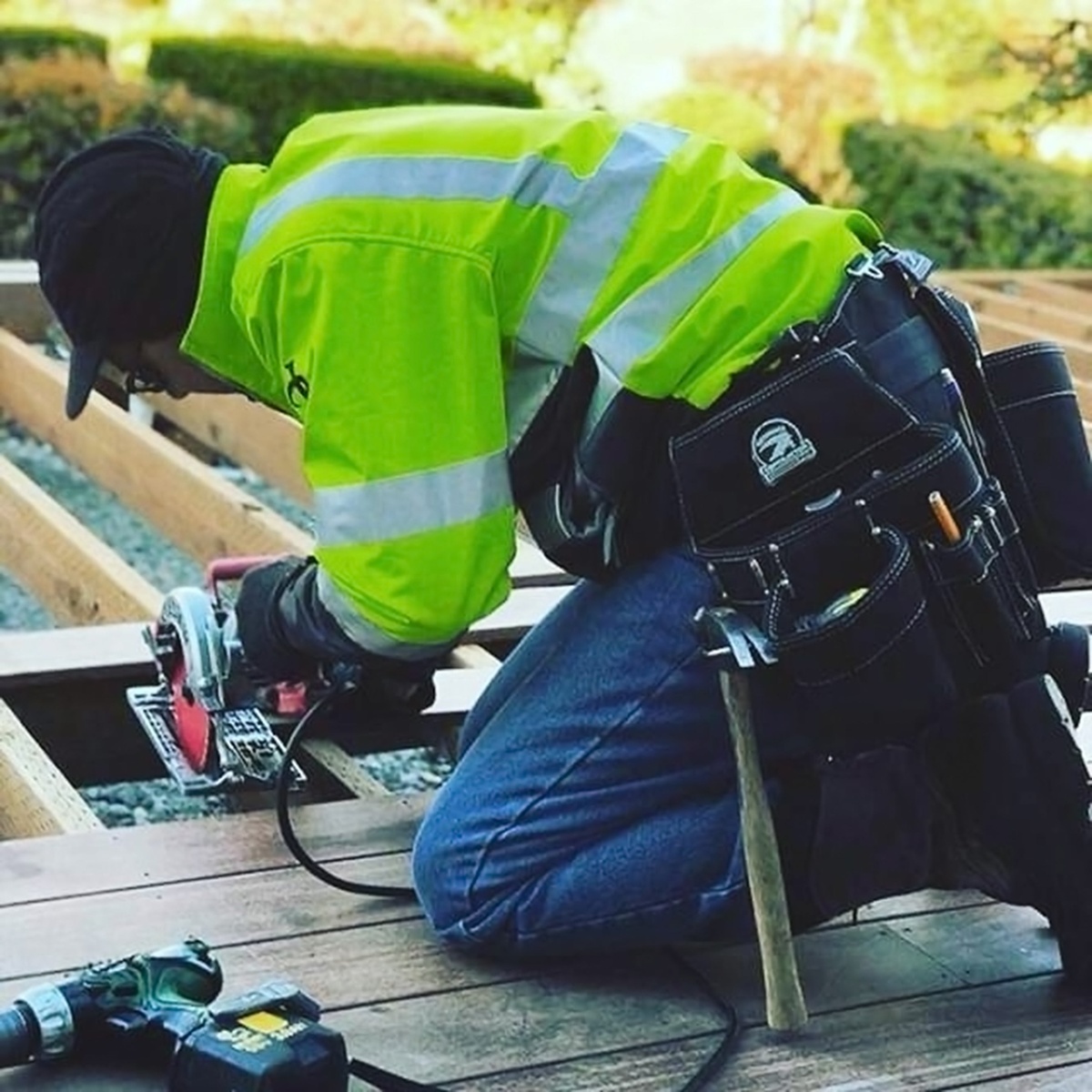 Gatorback B140 Professional Carpenters Tool Belt worn on a jobsite during deck framing while the user operates a circular saw on outdoor lumber