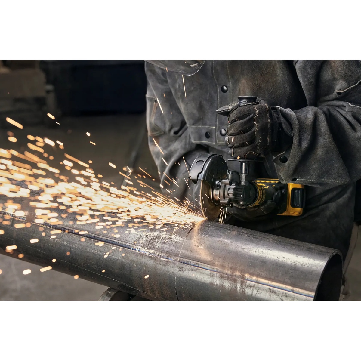 DeWALT DCG402B 20V MAX ATOMIC 4.5-in. Angle Grinder grinding steel pipe with side handle installed for better control on the job