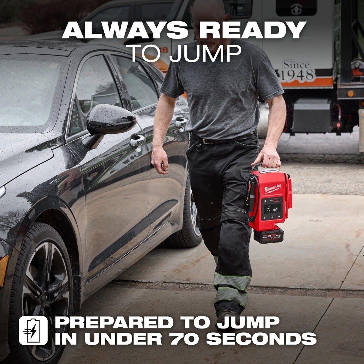 Milwaukee 3841-20 M18 HOTSHOT Jump Starter being carried to a disabled vehicle in a driveway for automotive battery service