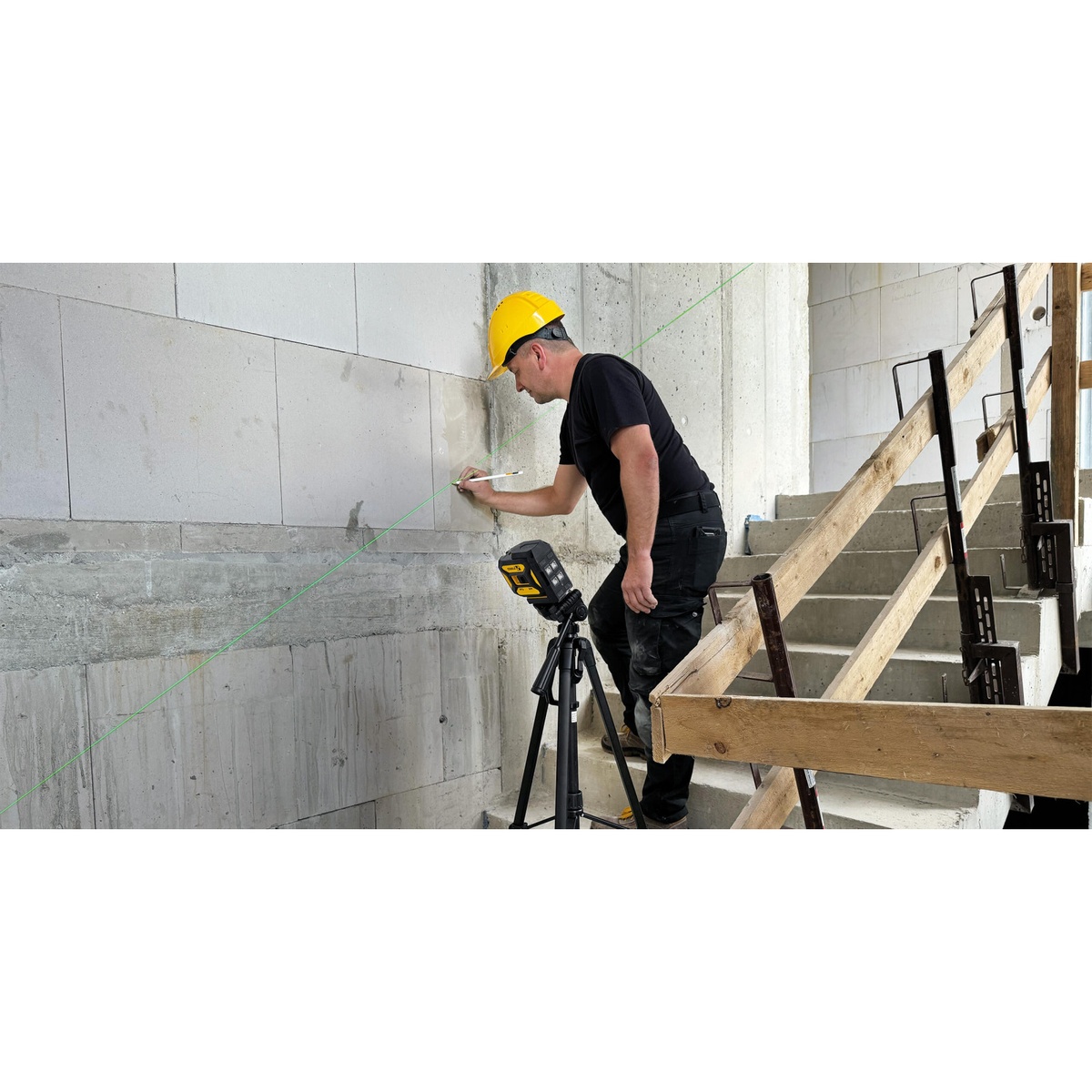 Stabila Cross line plus plumb dot laser LAX 320 G on a tripod projecting a green line for layout on a concrete wall in a construction interior