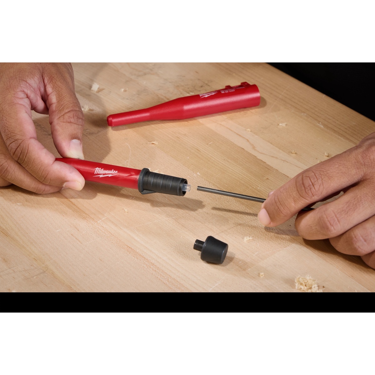 Milwaukee 48-22-3303 Mechanical Pencil Replacement Lead - Color being loaded into a Milwaukee mechanical pencil on a wood workbench during jobsite marking setup