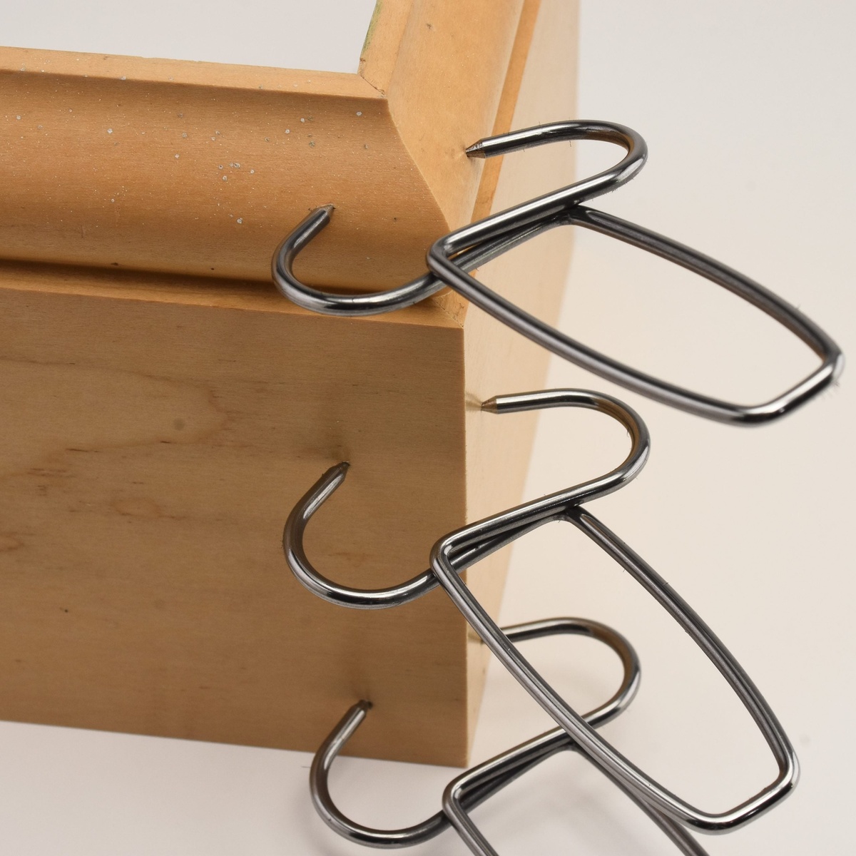 close-up of a spring miter clamp securing a wood molding corner during trim assembly in a shop setting