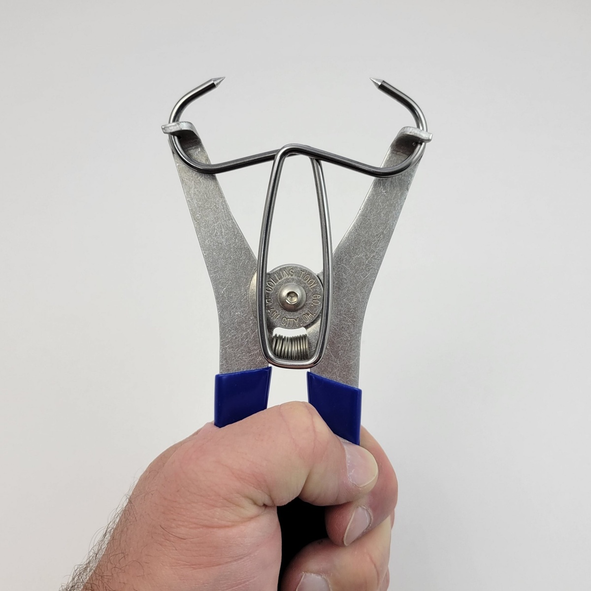 Collins 13-Pack of Miter Clamps & Pliers Kit plier tool opened in hand for applying spring miter clamps during woodworking glue-up