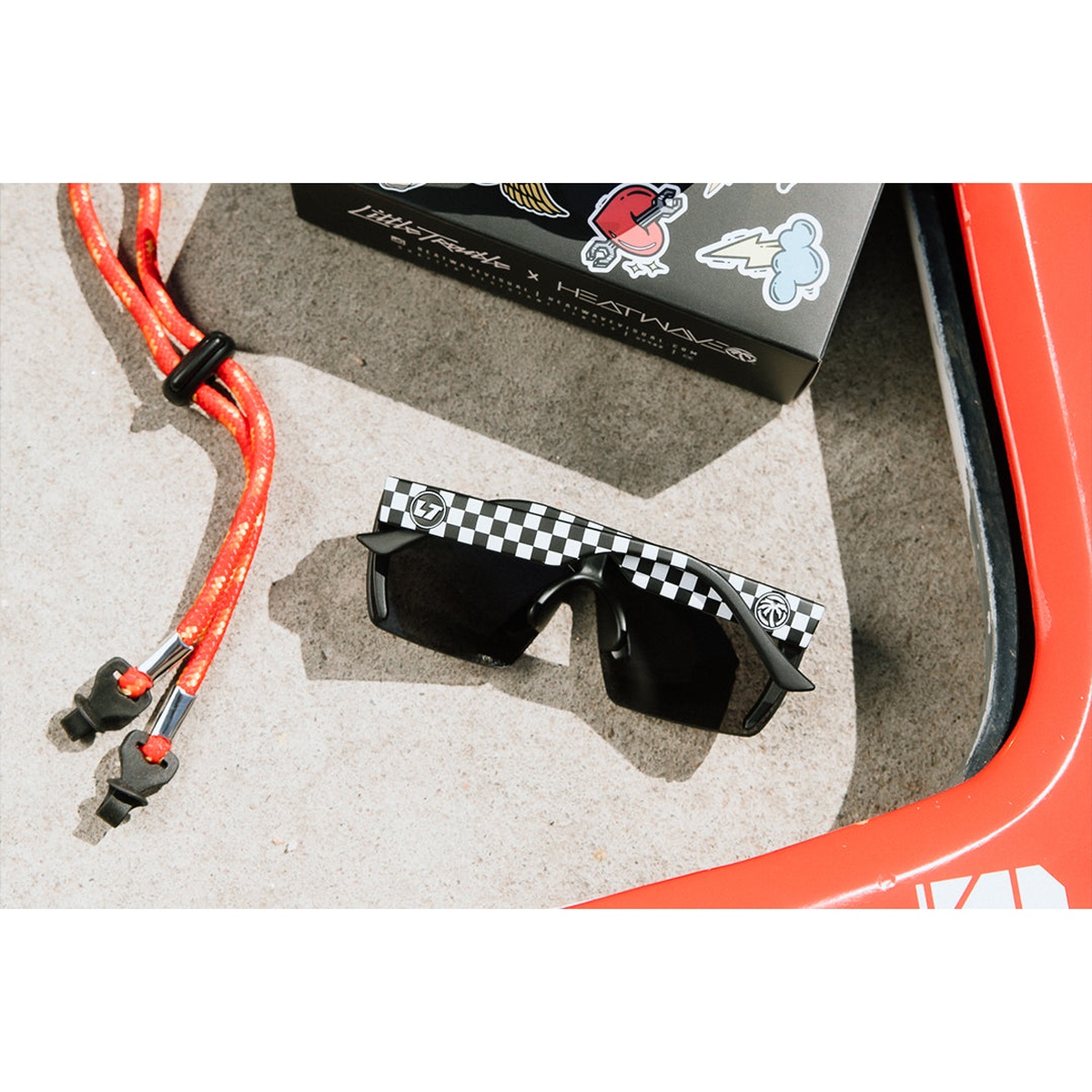 Kids Lazer Face Sunglasses Little Trouble X Heat Wave Checkered Flag with black shield lens and checkered temples set out for everyday outdoor use