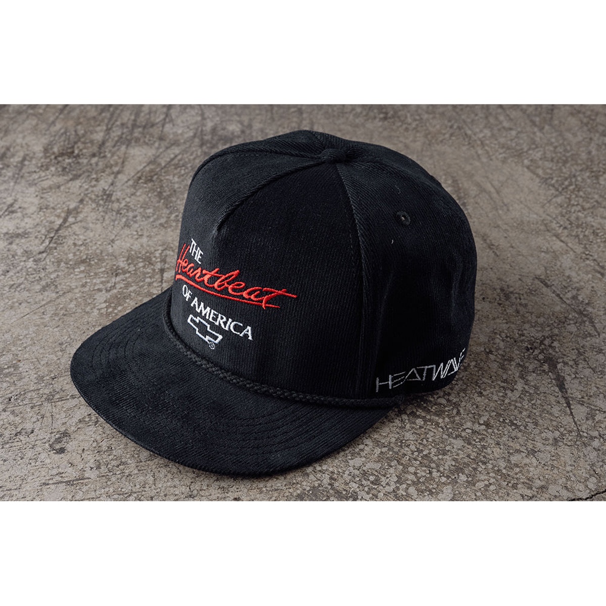 HWV Chevrolet Heartbeat of America Hat - BLACK Cord resting on a shop floor, showing the corduroy texture, structured front crown, and adjustable snapback styling for casual wear