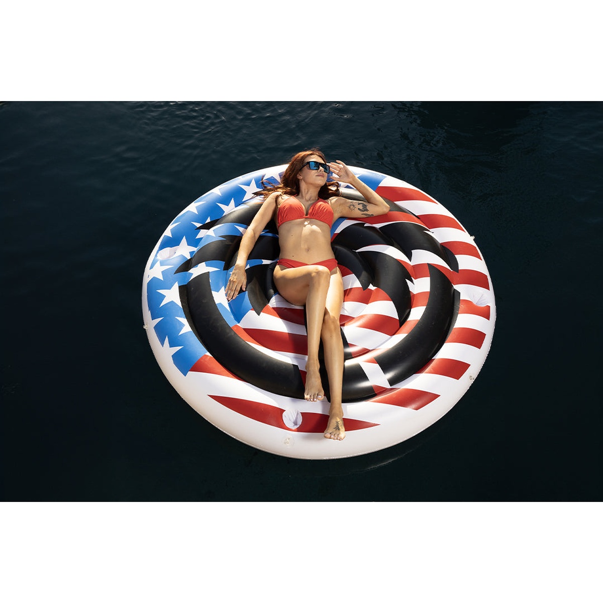 Heat Wave Ultimate Summer Floatation Device floating on water as a large patriotic pool float for relaxed lounging in a pool or lake setting