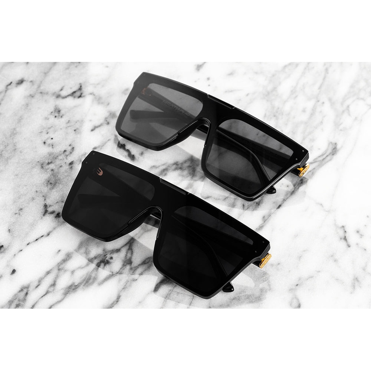 Heat Wave Visual Clarity Sunglasses: Ultra Black with oversized flat single lens and integrated brow bar on a marble surface