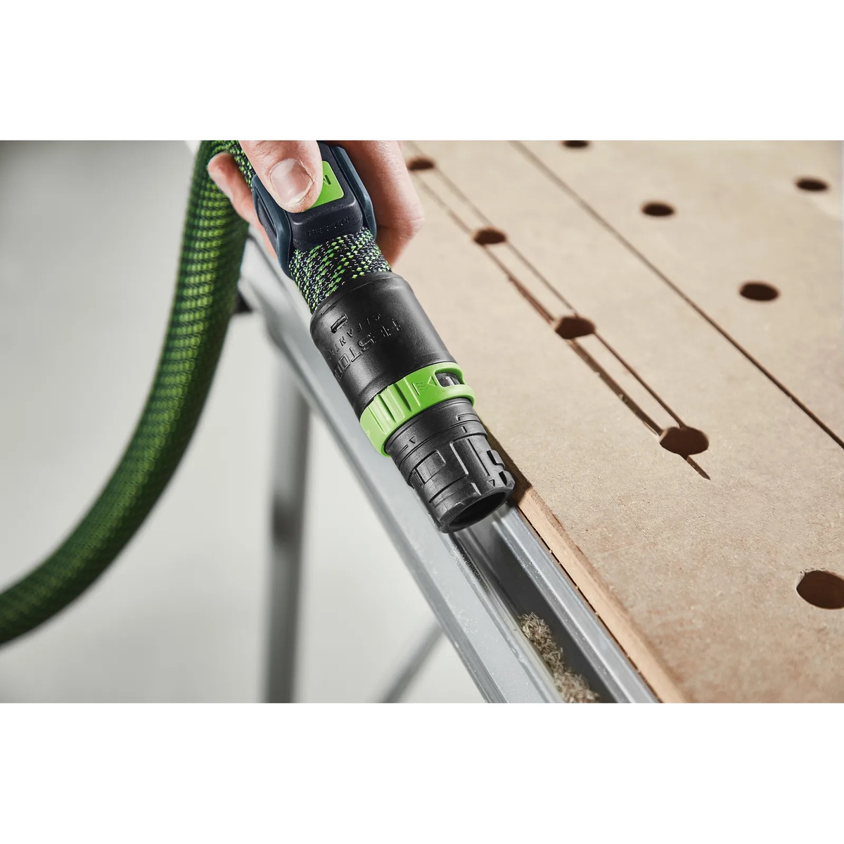 Festool suction hose with Festool 578499 Bluetooth Remote Control used for edge cleanup on a work table while connected to a CT dust extractor