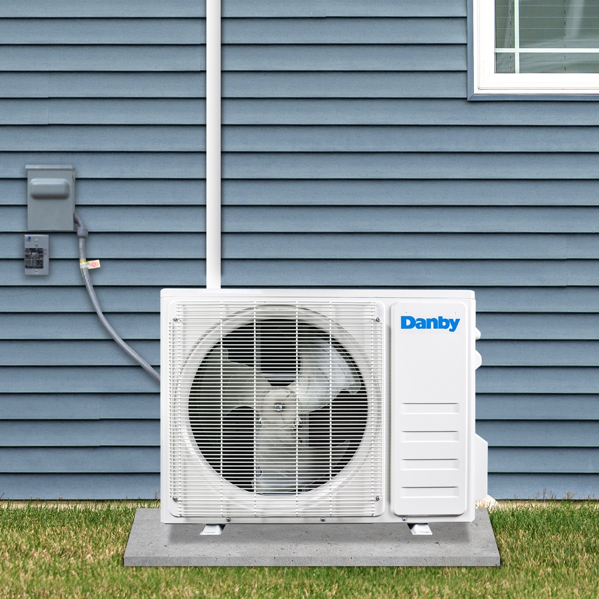 Outdoor condenser installed on a patio pad beside a home
