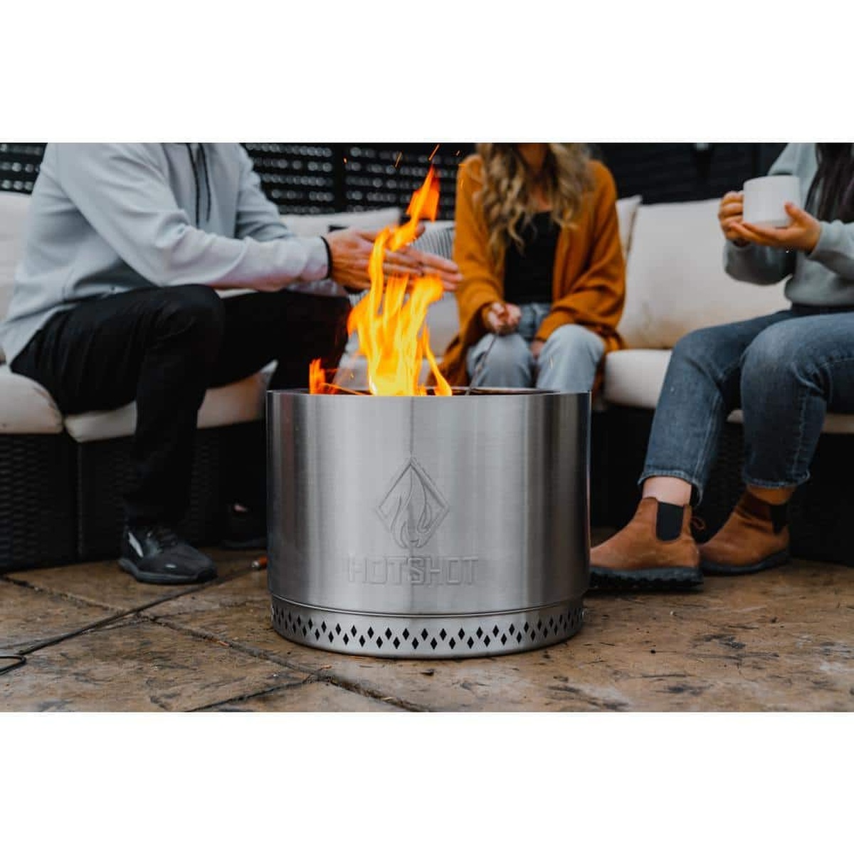 Lifestyle view of HotShot Explorer fire pit warming a group on a patio