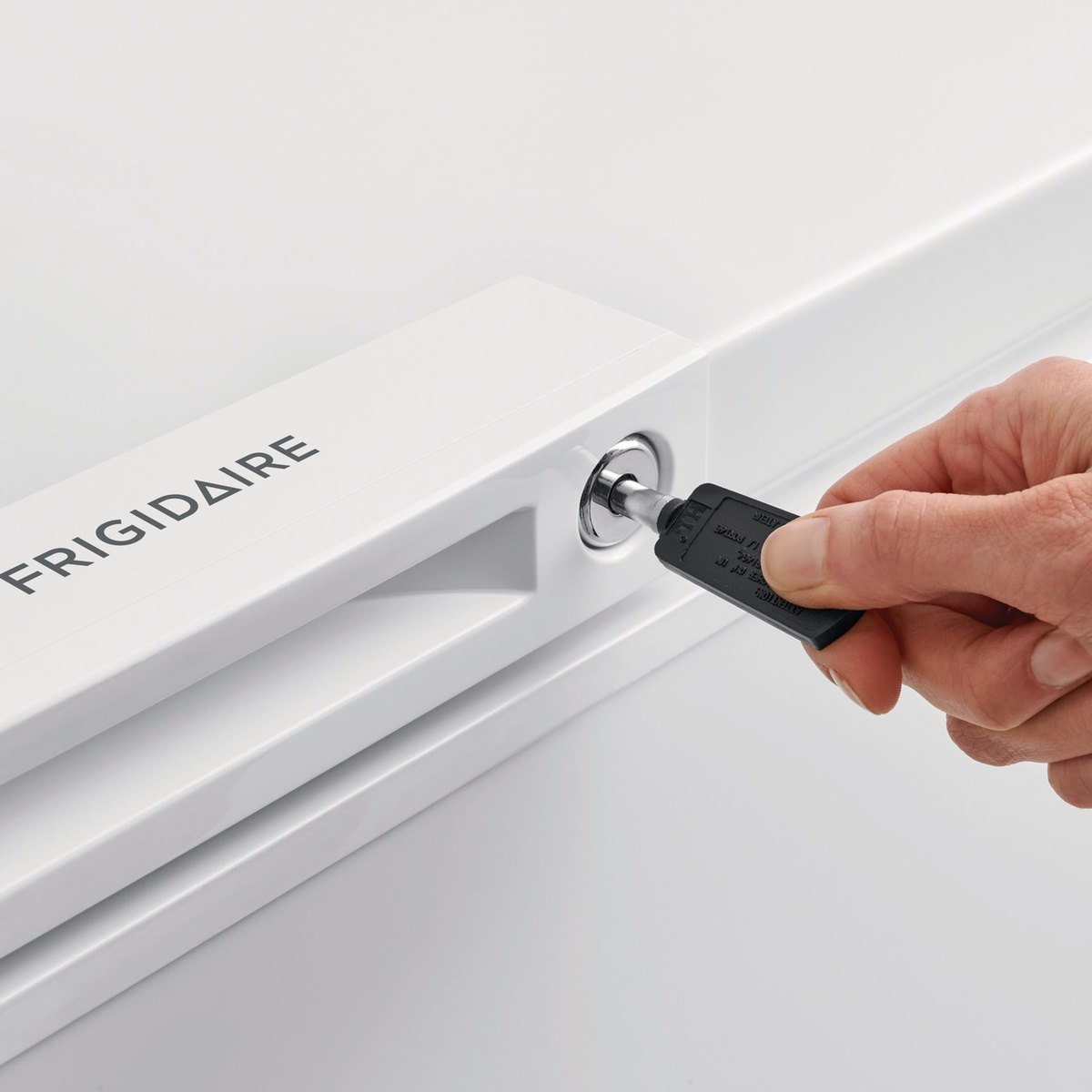 Close-up of the Frigidaire lock being engaged with a pop-out key on the handle.