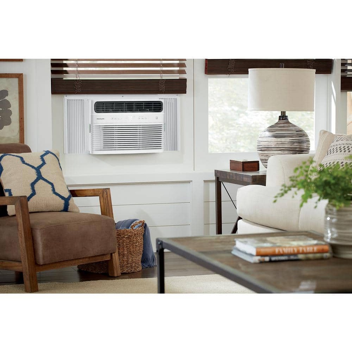 Window air conditioner cooling a bright living room with sofa and lamp nearby.