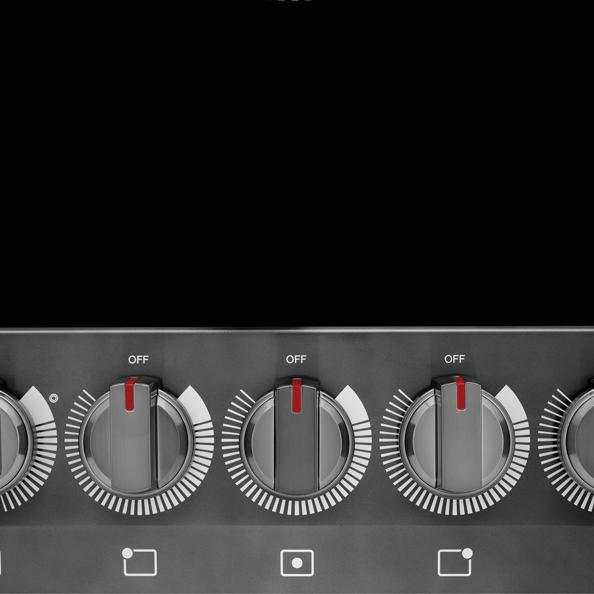 Detail of five control knobs with printed element icons beneath the ceramic glass surface