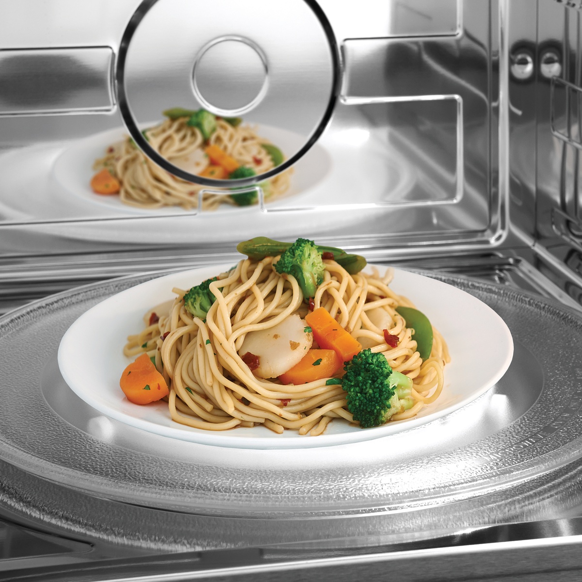 Food reheating evenly on glass turntable inside bright LED-lit cavity