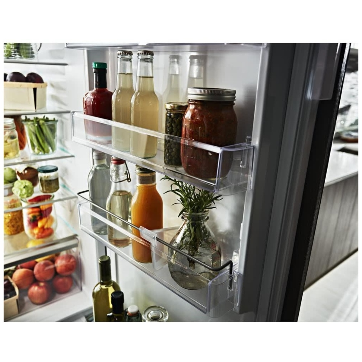 Close-up of refrigerator door bins holding bottles, jars and herbs