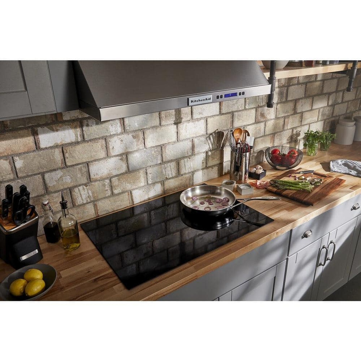 Kitchen-installed black glass cooktop with pan cooking on countertop