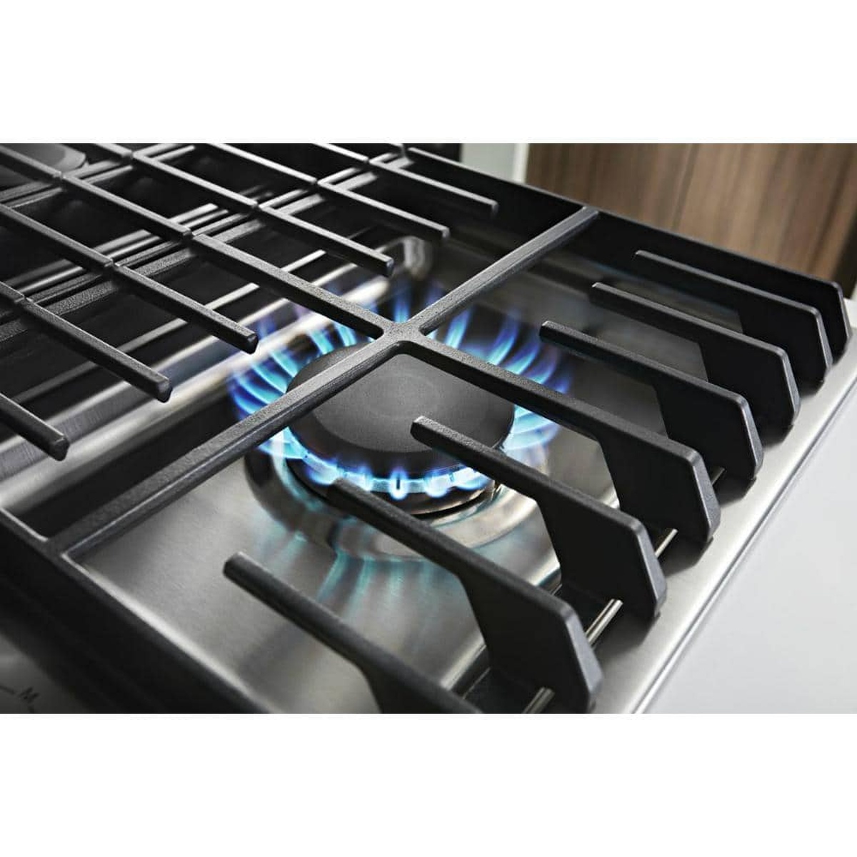 Close view of gas burner with blue flame under cast-iron grates.