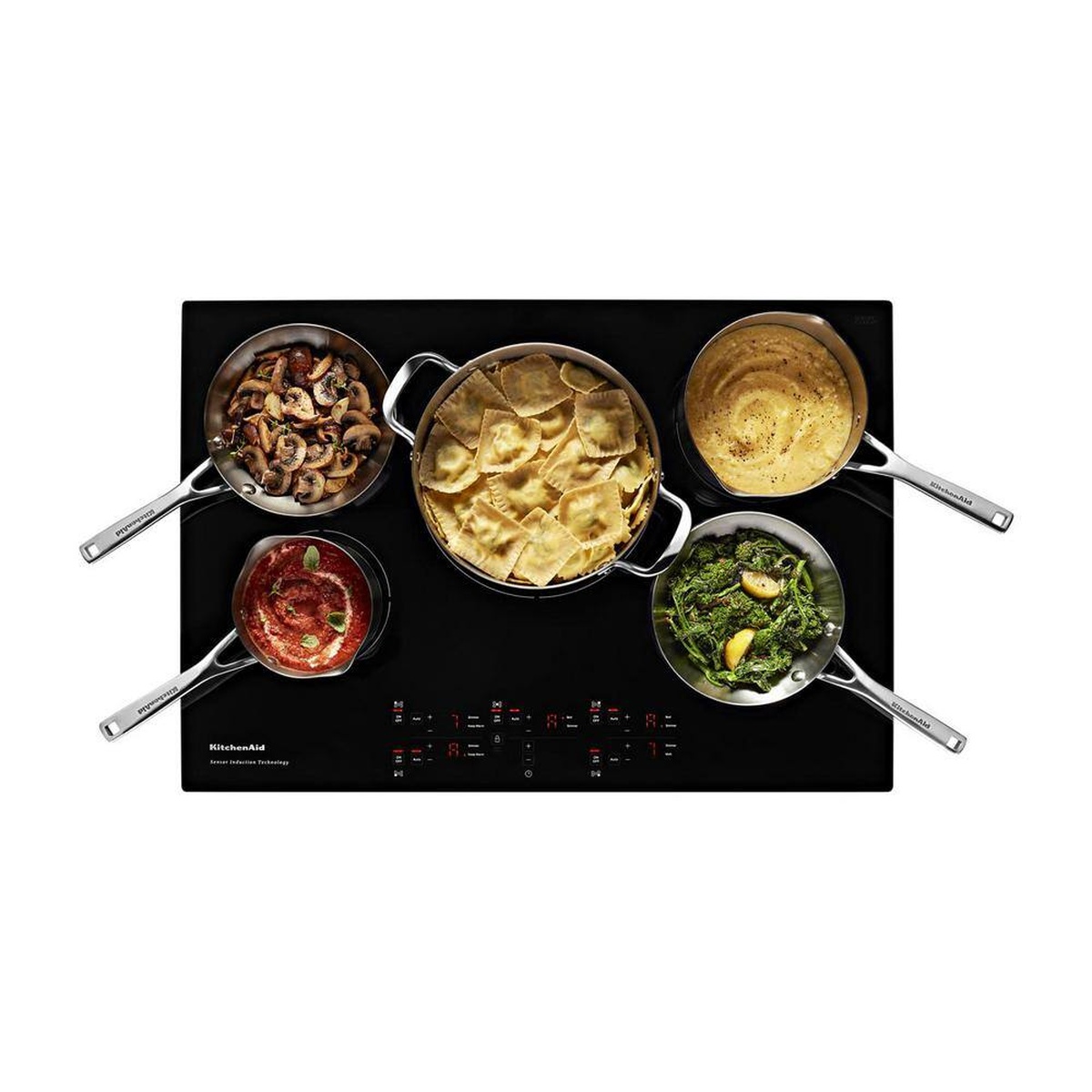 Top-down view of the cooktop actively heating five pans with different dishes at once.