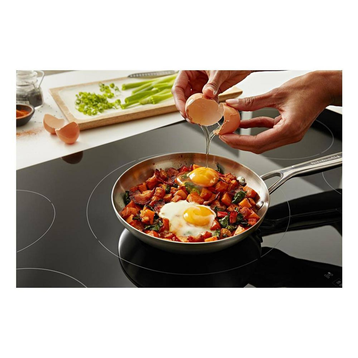 Pan on the induction element with eggs being added for precise low-and-slow cooking.