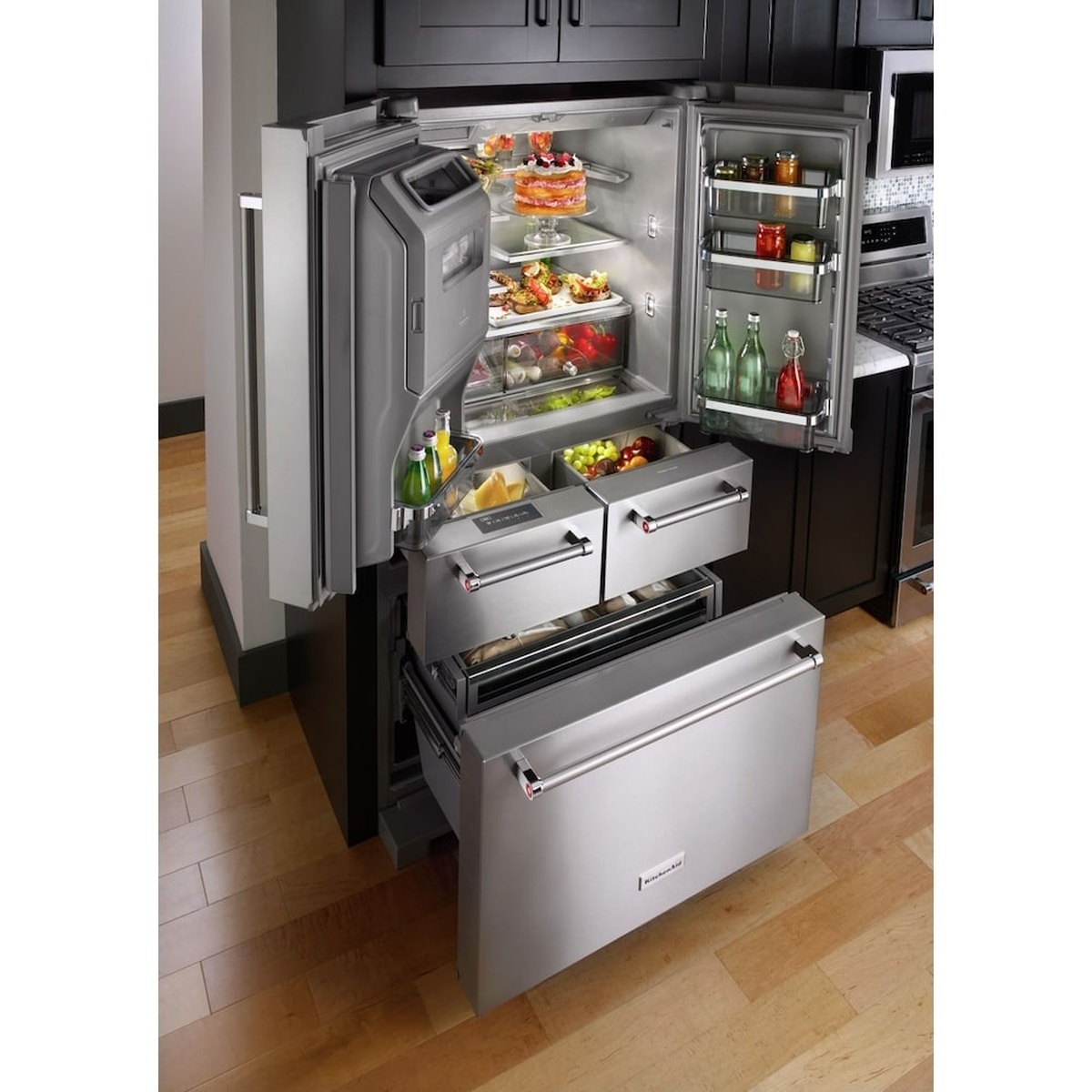 KitchenAid multi-door refrigerator with doors and drawers open showing interior shelves and pantry drawers