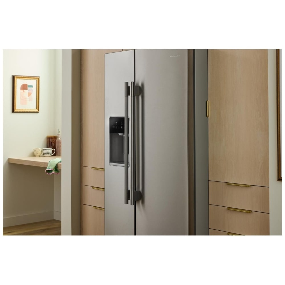 Counter-depth KitchenAid refrigerator installed flush within light wood cabinetry