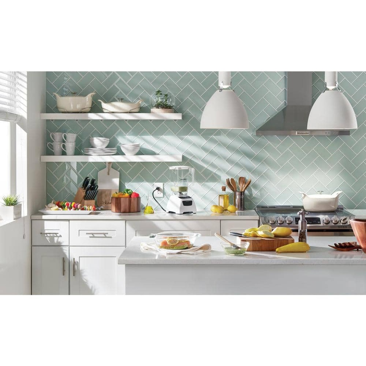 Lifestyle kitchen scene with the KitchenAid wall-mount hood above a range in a bright, modern space