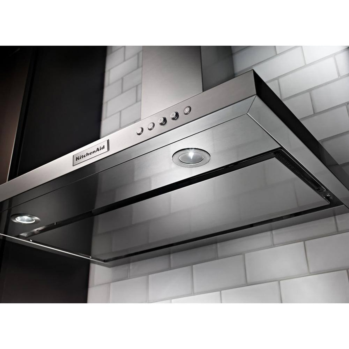 Lifestyle angle of the KitchenAid 36-inch wall-mount canopy hood with dual LEDs and control buttons over subway tile.