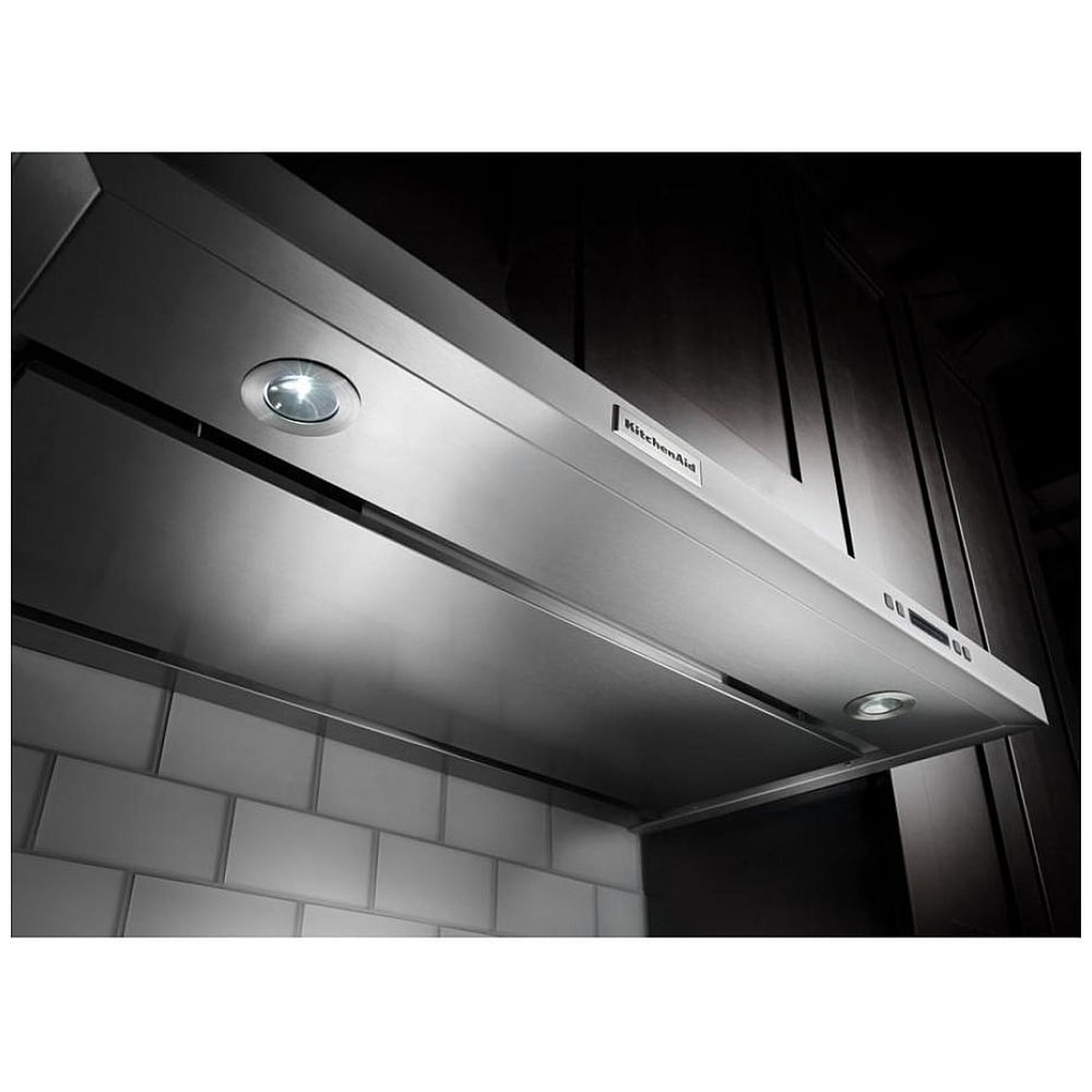 Angled under-cabinet range hood installed beneath cabinetry showing illuminated light and underside capture area