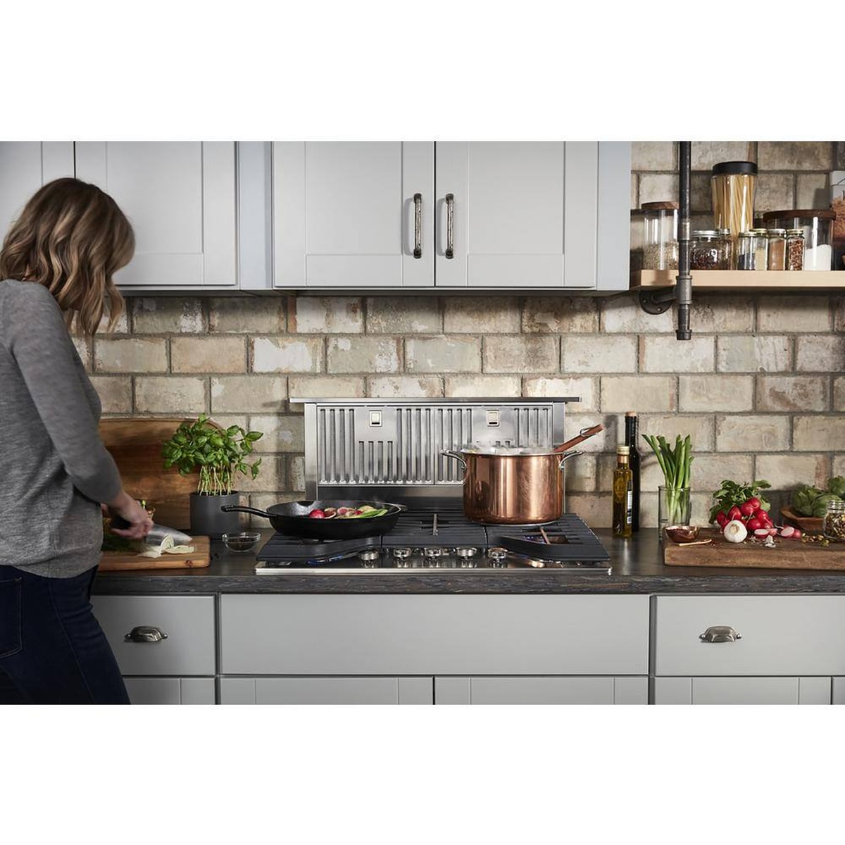 Downdraft vent in a modern kitchen clearing steam from pots on the cooktop.