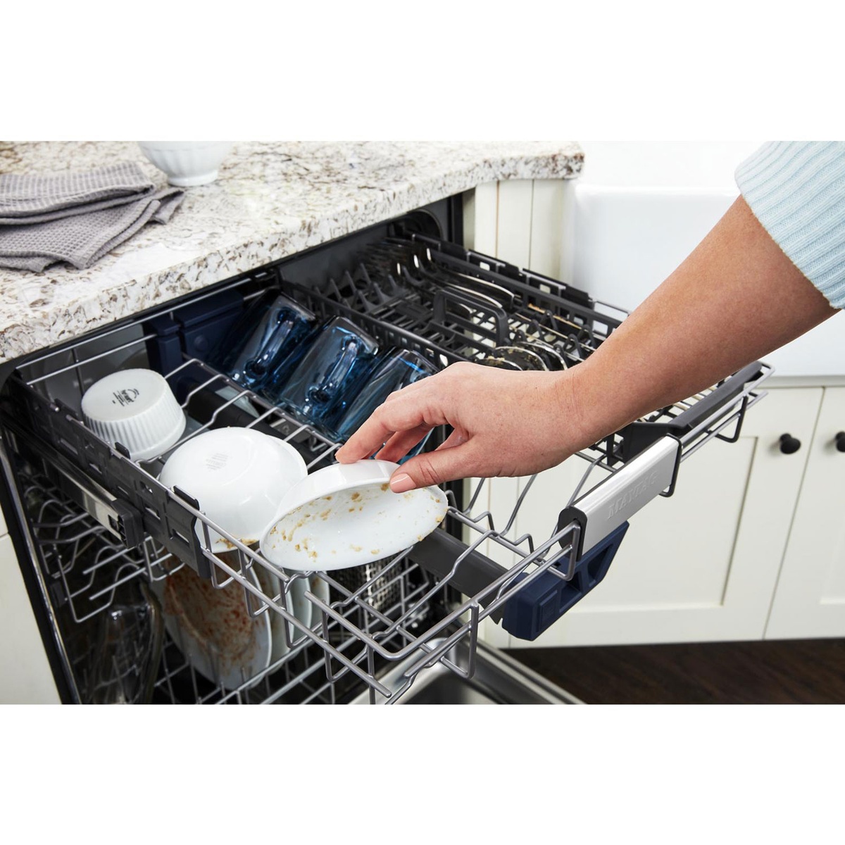 User loading bowls and cups into the third rack of the dishwasher