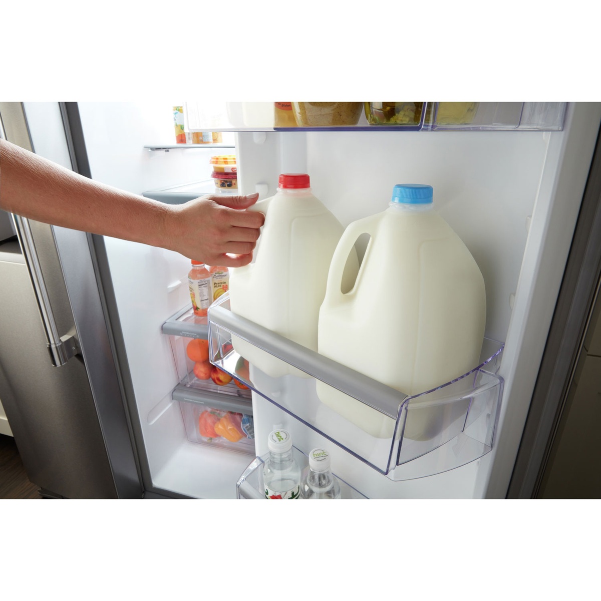 Hand placing gallon jugs in the large door bin