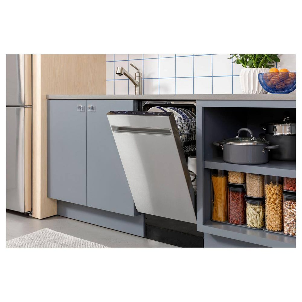 Haier 18-inch dishwasher installed undercounter in a modern kitchen, door partially open with clean dishes inside.