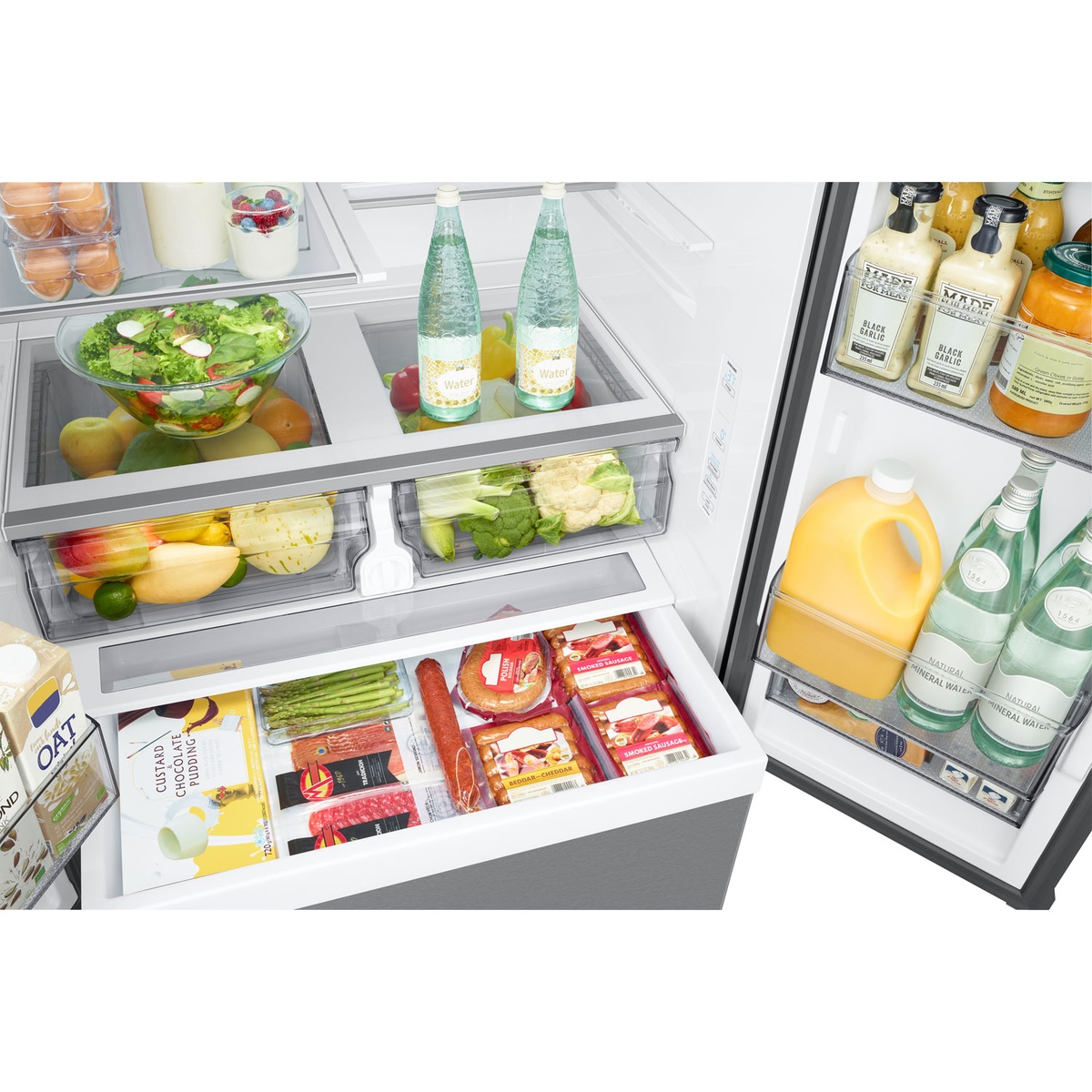 Close-up of refrigerator mid-shelves and drawers with salad bowl, beverages, and produce organized