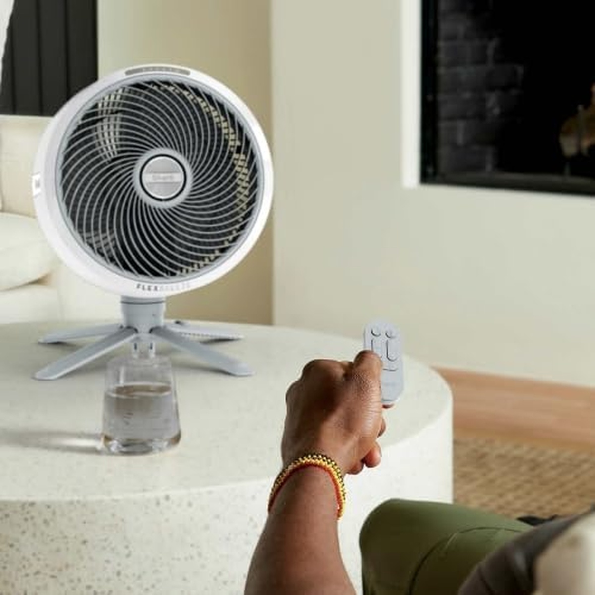 Tabletop fan on a coffee table with a person using the remote control