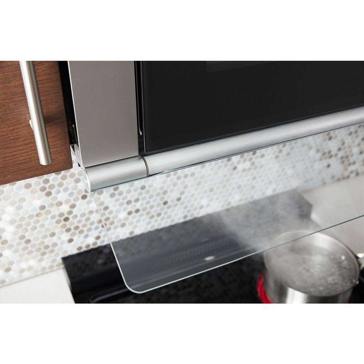Flip-out glass vent visor directing steam toward the vent under the microwave.