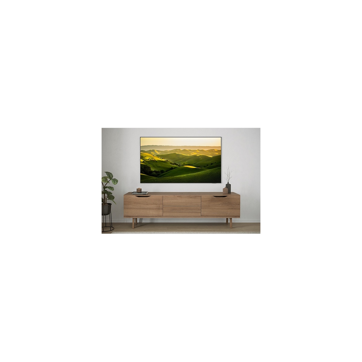 Lifestyle scene with the TV mounted on a wall above a wooden media console displaying a scenic landscape.