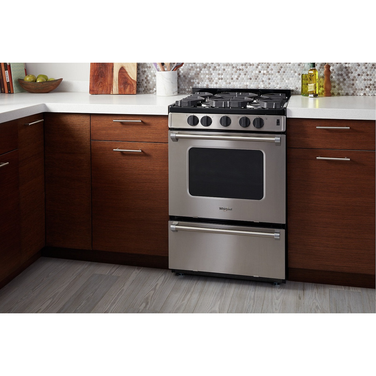 Whirlpool 24-inch gas range installed between base cabinets in a modern kitchen.
