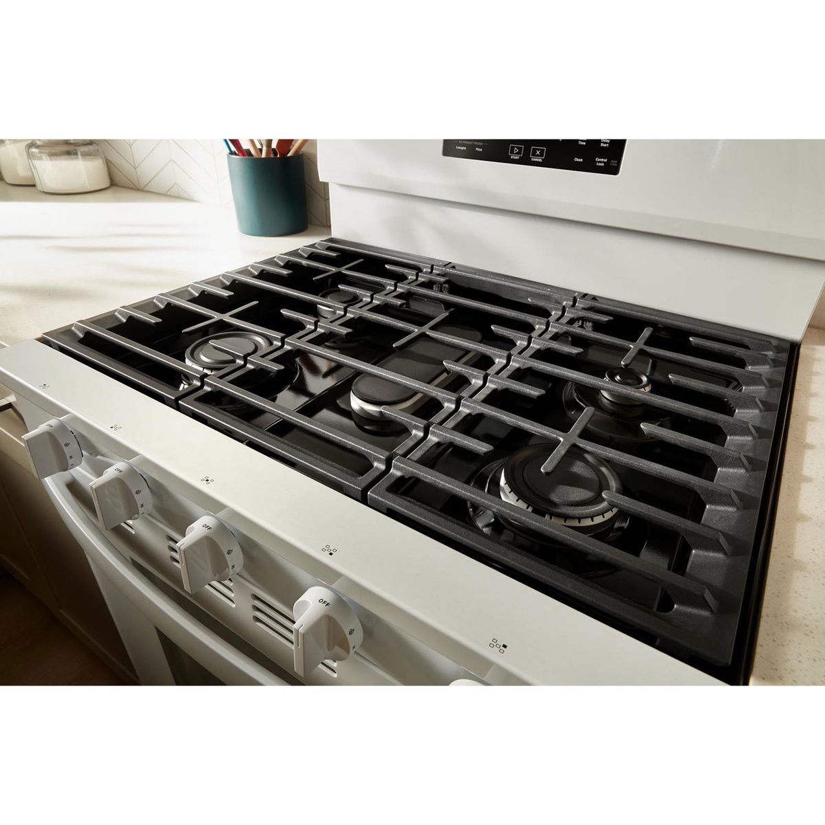 Edge-to-edge cast-iron grates covering five gas burners on the cooktop.
