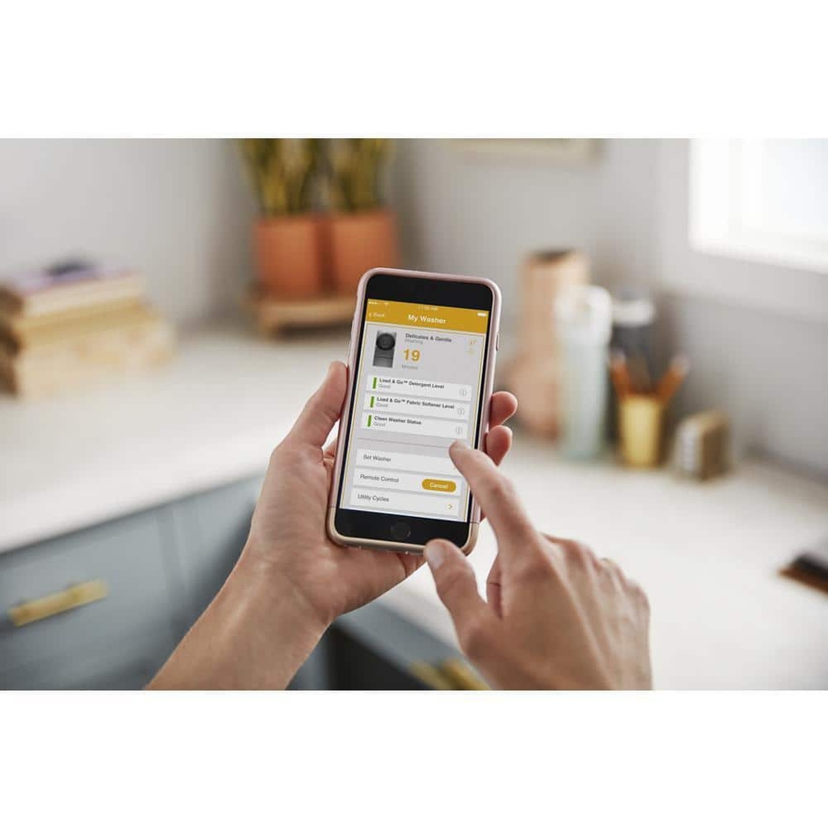 Smartphone showing Whirlpool app with remote washer controls